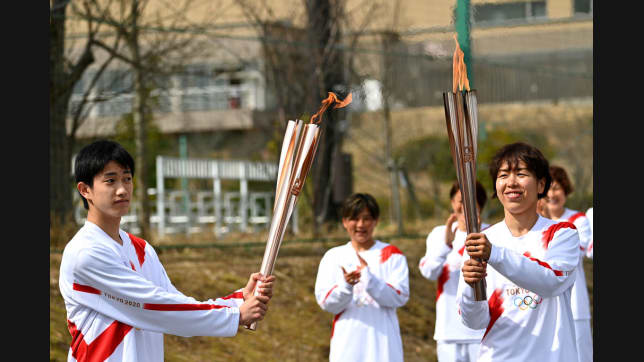 La portadora Azusa Iwashimizu (dcha.), miembro de la selección japonesa ganadora de la Copa del Mundo 2011 de fútbol femenino, pasa la llama al estudiante Asato Owada. (Imagen por Philip Fong - Pool/Getty Images)